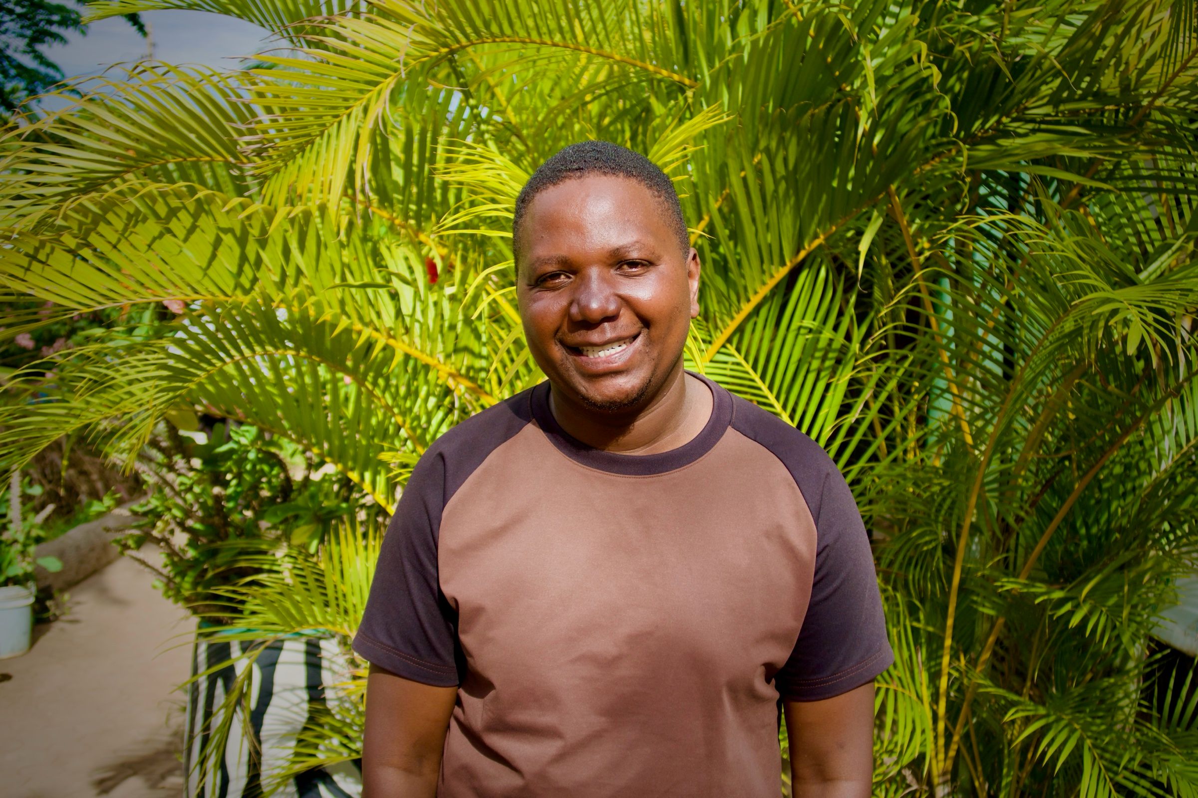 Joseph, Kilimanjaro guide, smiling in front of palm trees
